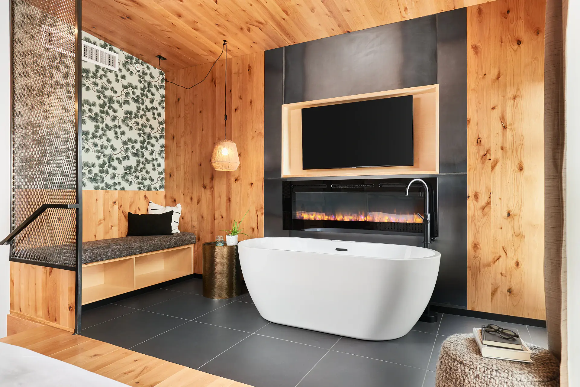 A boutique guest room with a soaking tub, fireplace, and warm wood walls at Kinship Landing in Colorado Springs