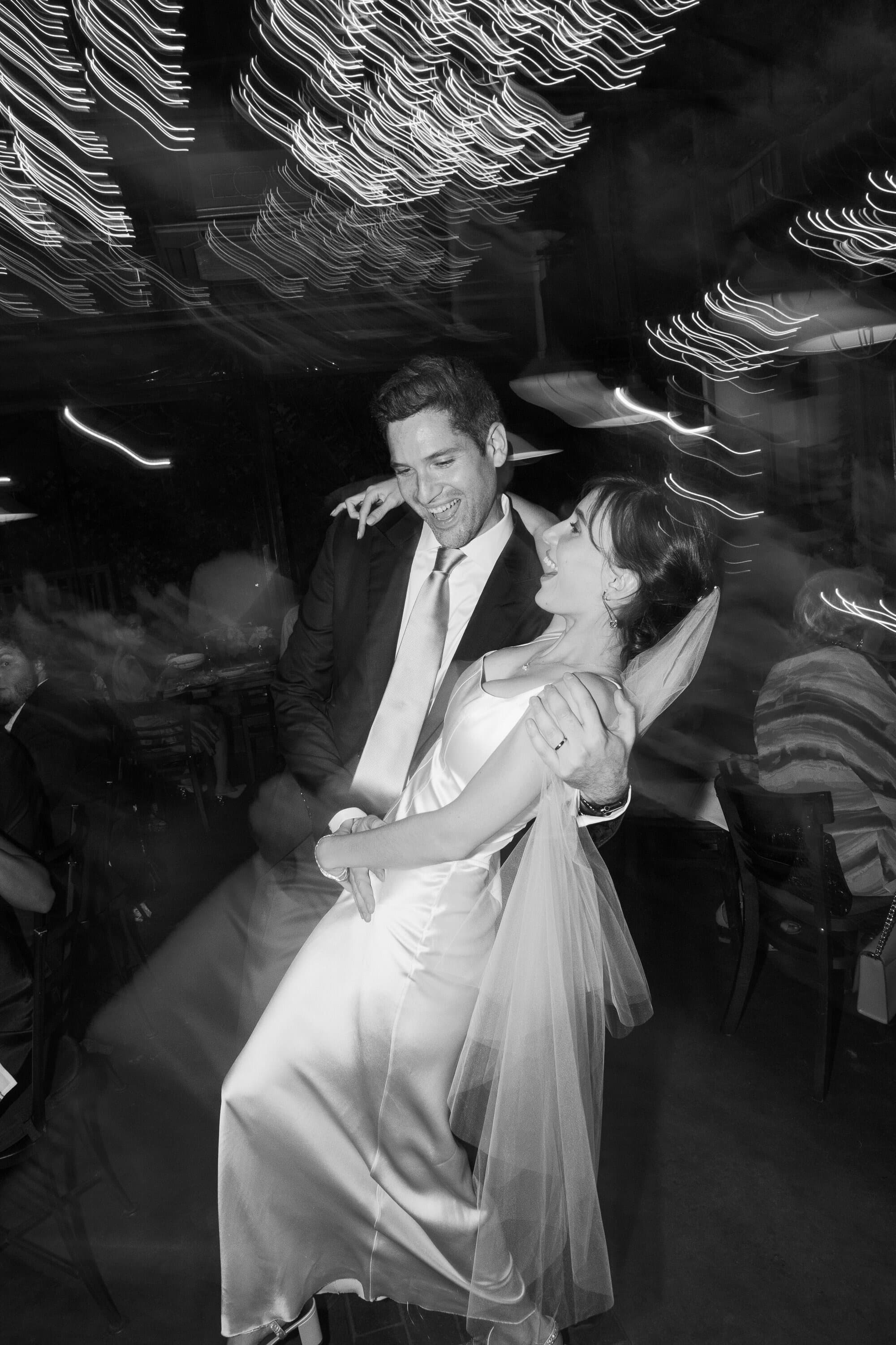 Bride and groom sharing a candid first dance under string lights, captured by editorial wedding photographer Sabra Photo