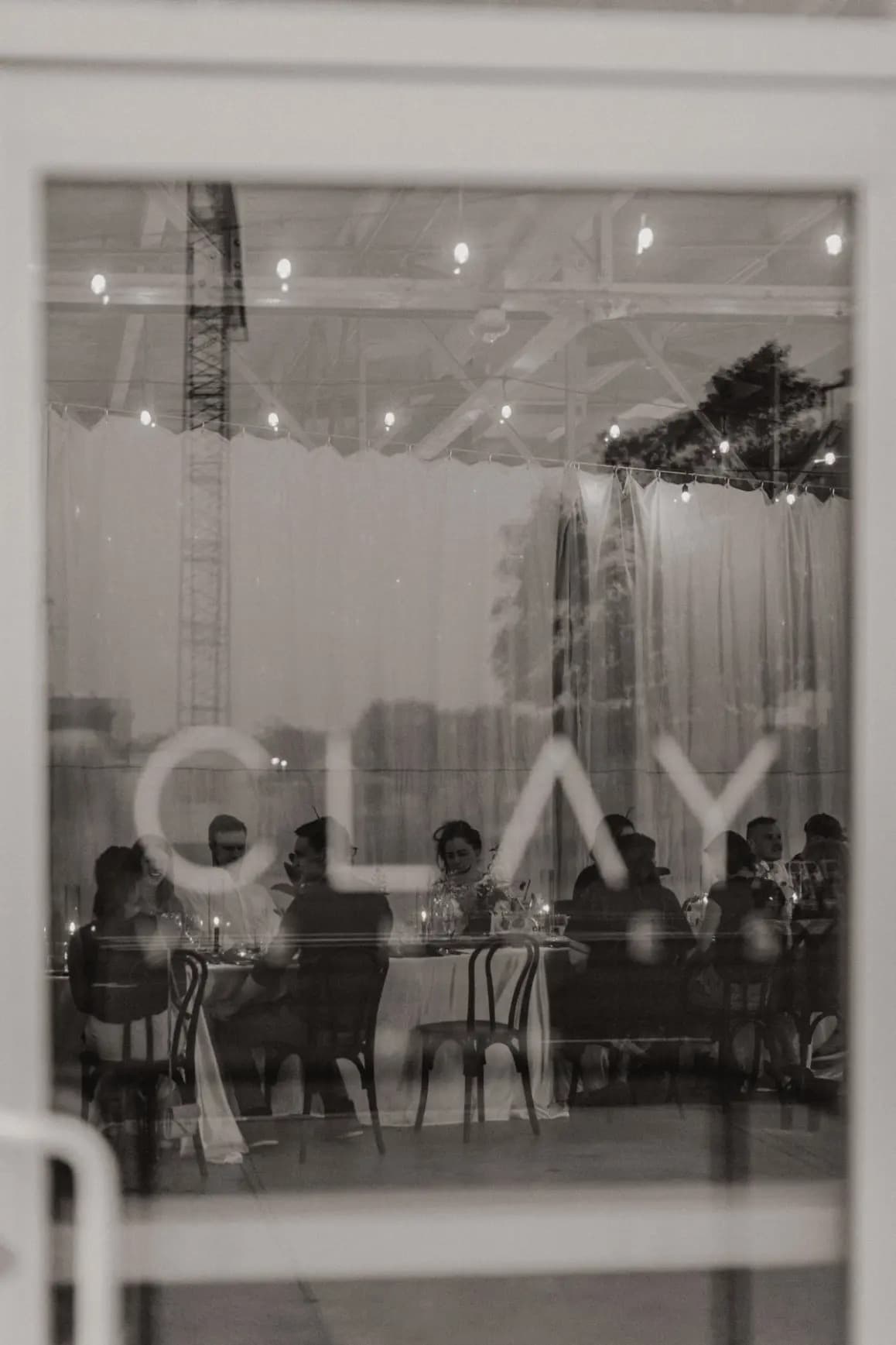 Wedding reception viewed through a glass door etched with the CLAY logo at Clay Venues in Colorado Springs, Colorado