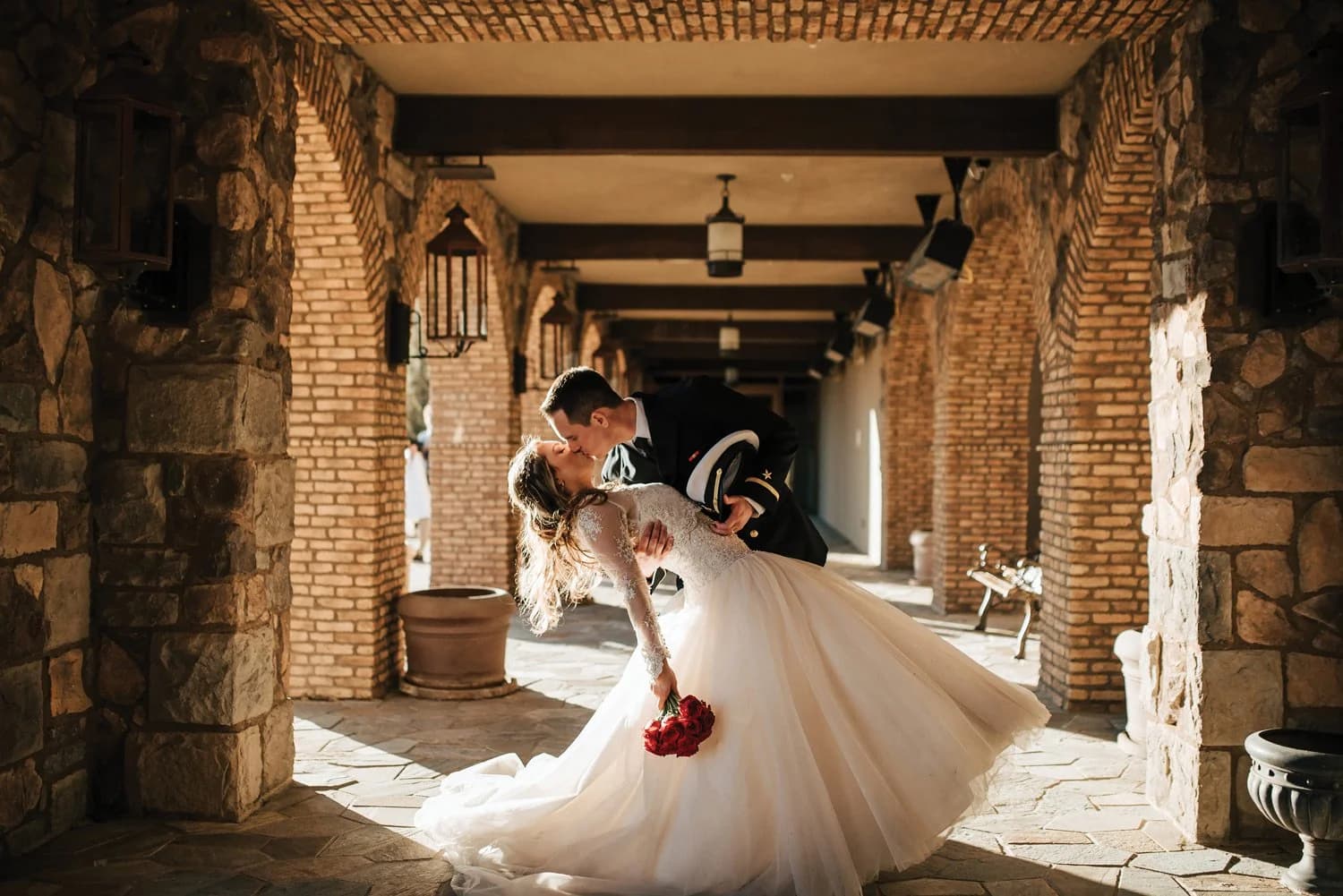 Bride and groom sharing a dip kiss in a stone Tuscan-style corridor at Flying Horse Resort & Club in Colorado Springs, Colorado