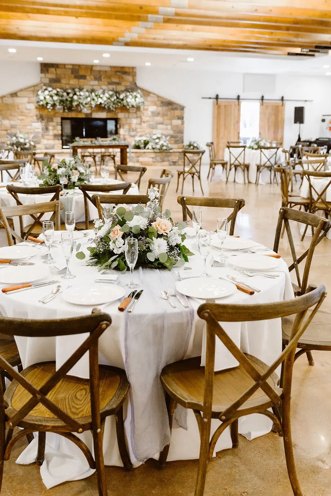 Reception hall with round tables and a stone fireplace at Hearth House Venue in Monument, Colorado