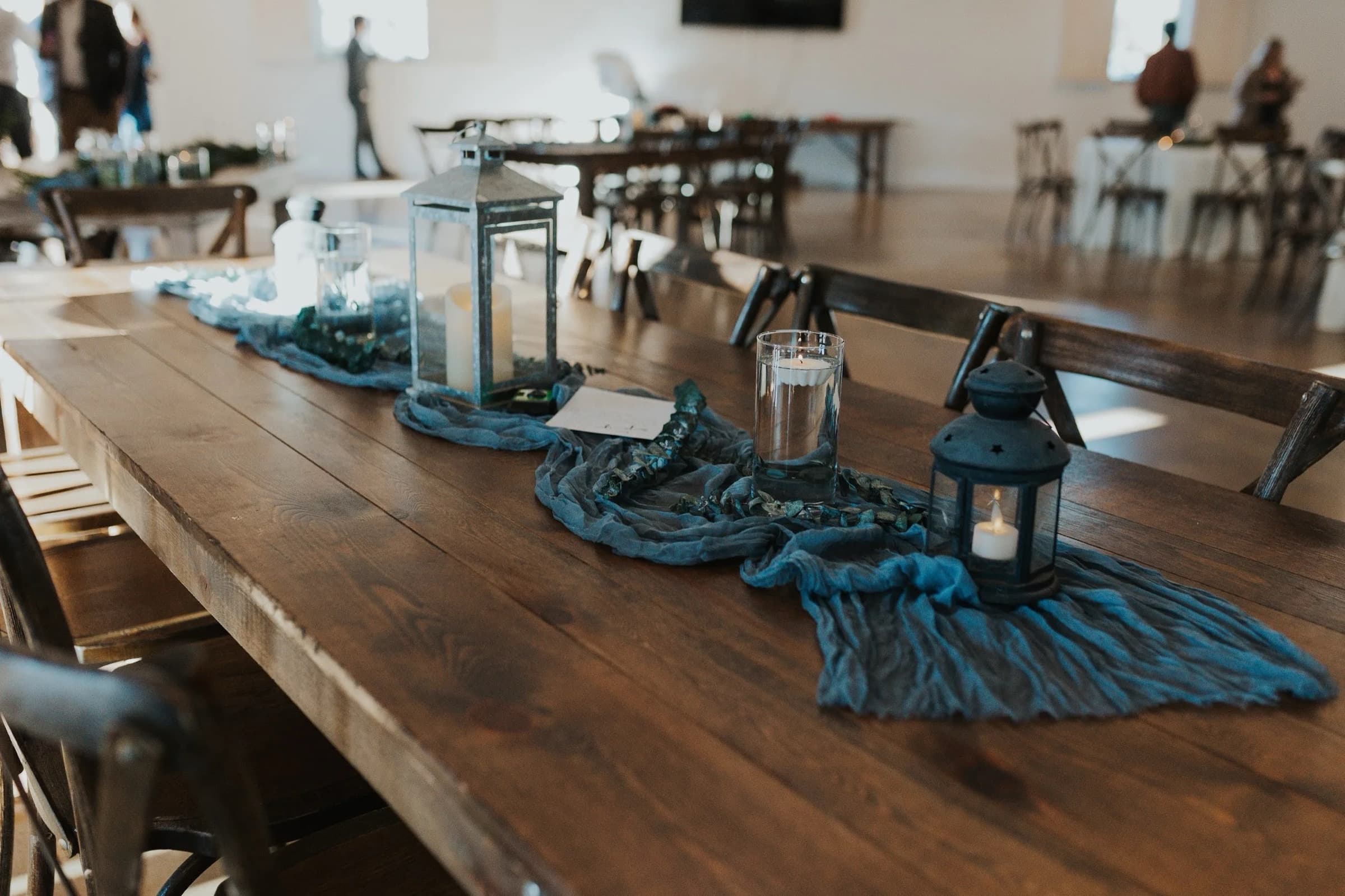 Farm-table tablescape with lanterns and blue runners at Hearth House Venue in Monument, Colorado