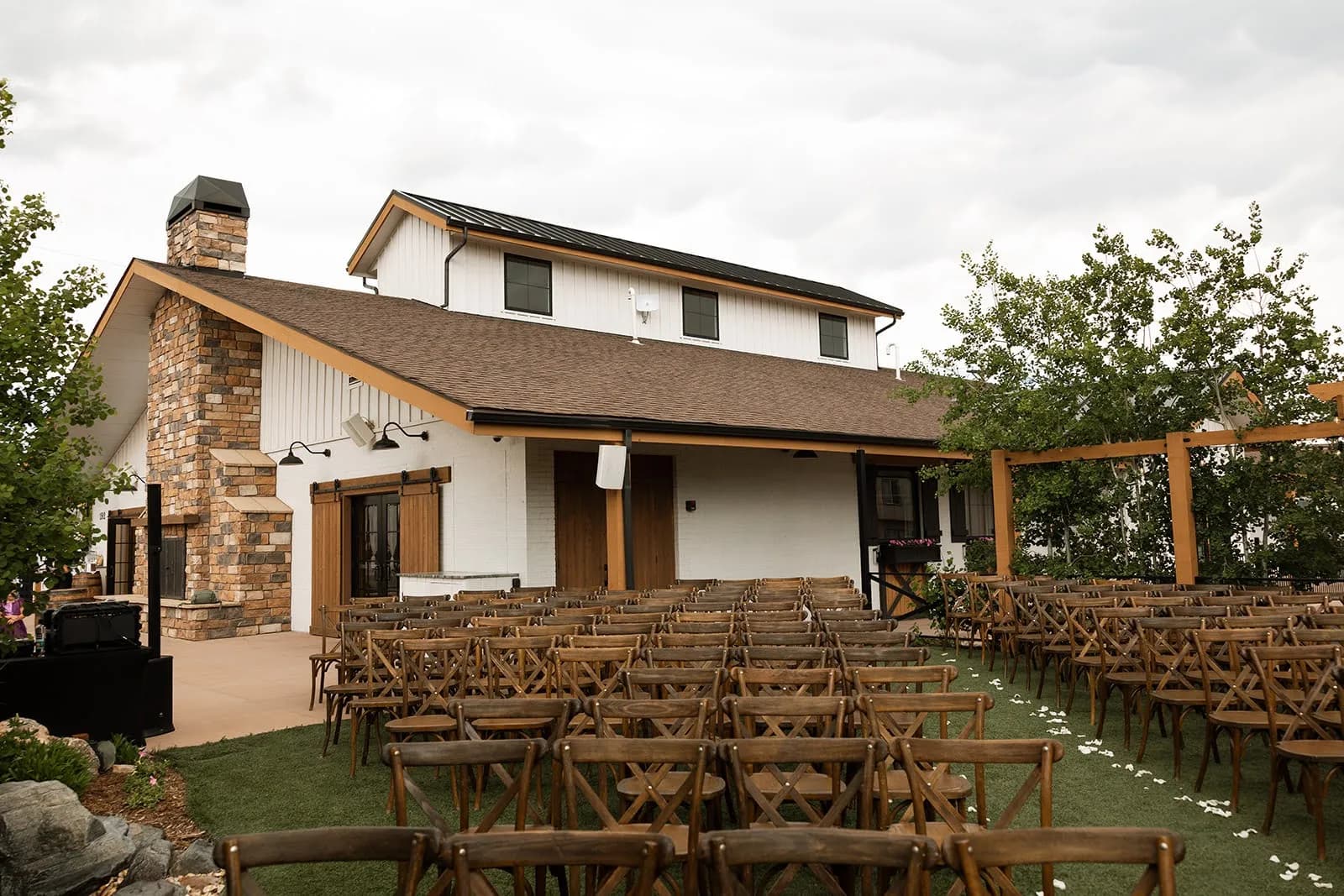 Outdoor wedding ceremony set with wooden chairs in front of the modern farmhouse at Hearth House Venue in Monument, Colorado
