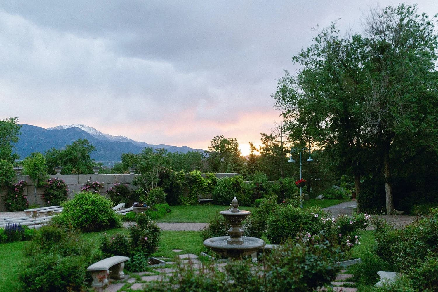 Terraced flower gardens with a stone fountain and Pikes Peak at dusk at Hillside Gardens & Event Center near Monument, Colorado