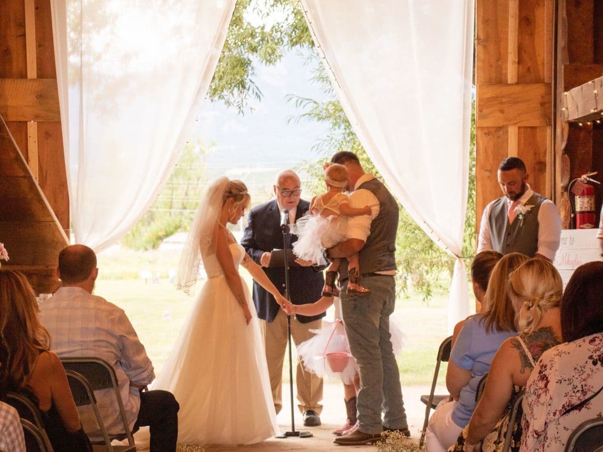 Wedding ceremony inside the restored Reynolds Ranch Hay Barn with draped doorway and mountain views in Monument, Colorado
