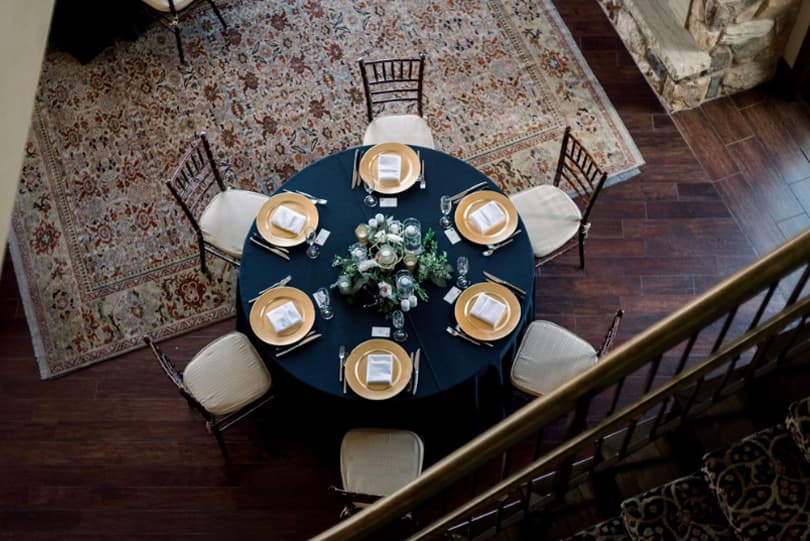 Overhead view of a reception table with gold chargers on a patterned rug at The Pinery at the Hill in Colorado Springs, Colorado