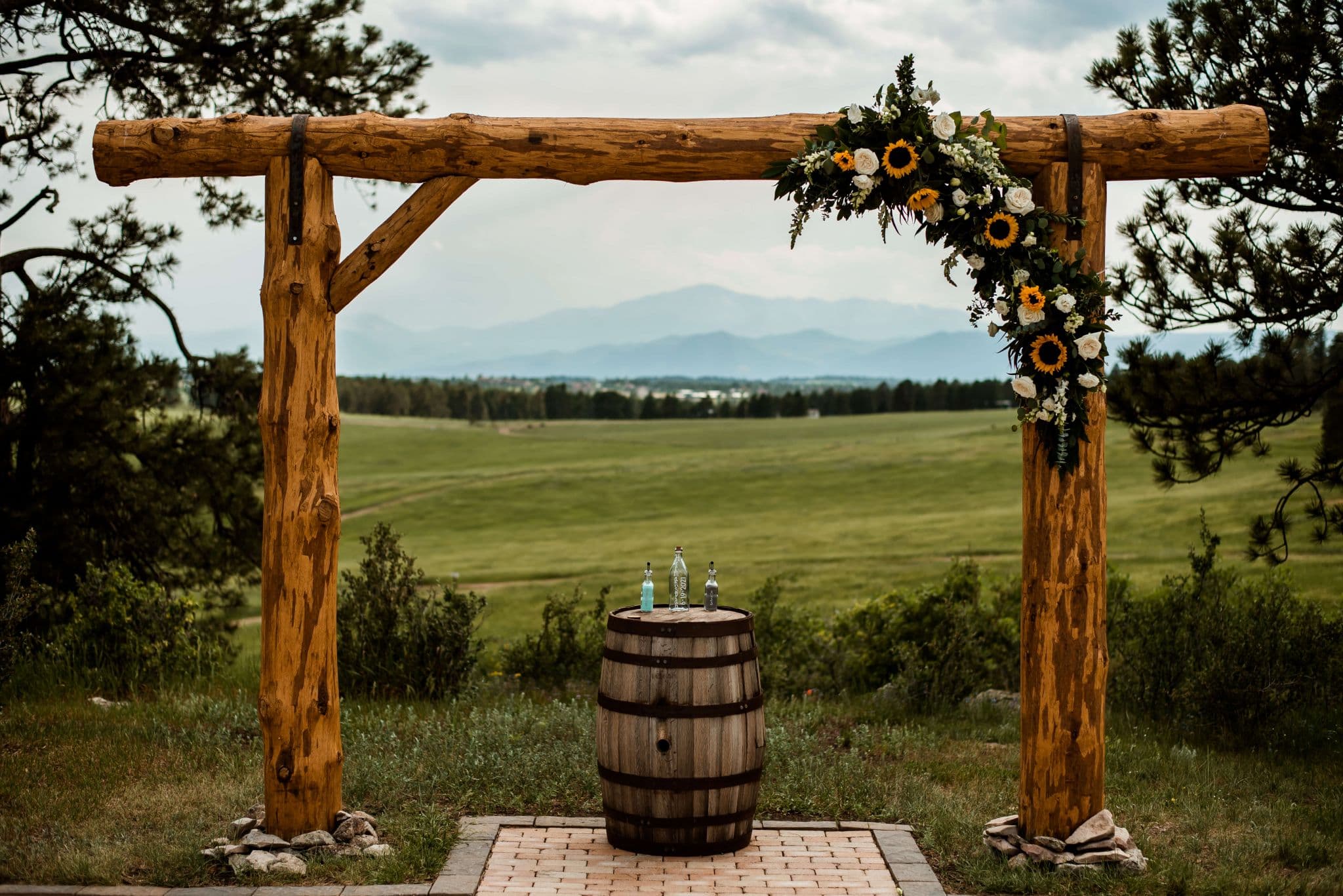Wooden wedding arch decorated with sunflowers over a wine barrel at Younger Ranch in Monument, Colorado